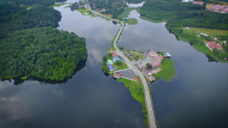 Toma-Aérea-Del-Lago-Raban-Con-Reflejo-Del-Cielo-Y-Camino-En-El-Lago-En-Malasia