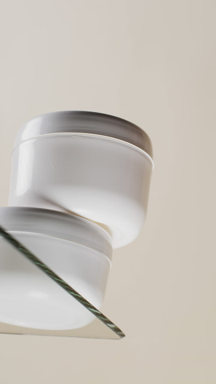 video vertical de bañeras de productos de belleza en estantería de vidrio con espacio de copia en fondo blanco