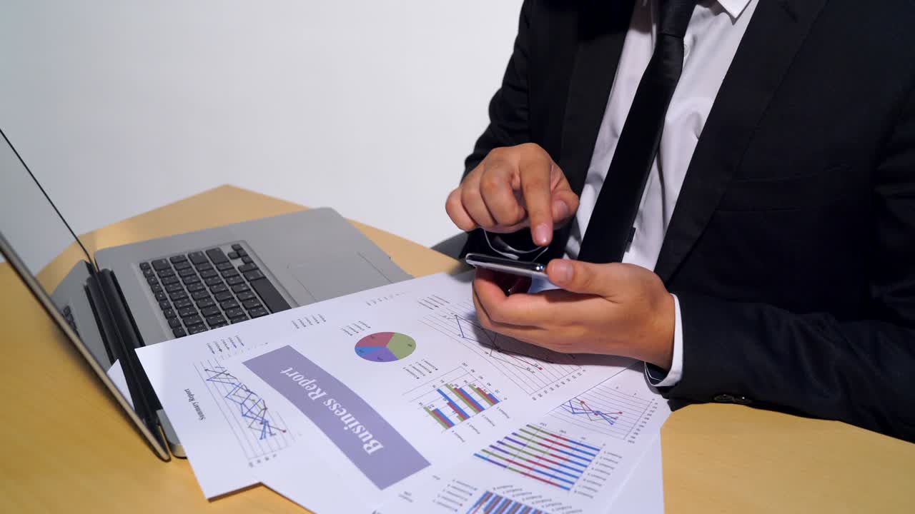4K Business man touch the mobile phone on the meeting table team to work in the office, white paper is the document plan summary report, the paper on the computer laptop.