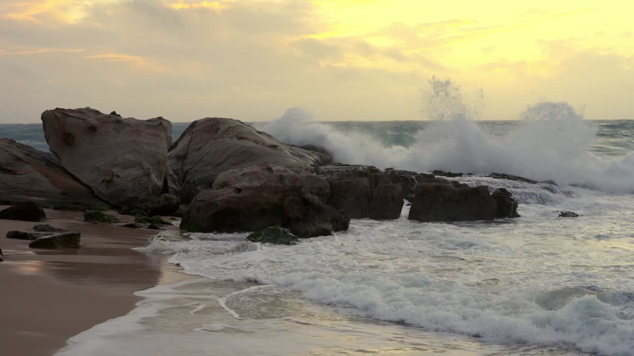 las olas chocando al crepúsculo en la playa rocosa