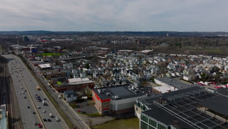 Aerial-shot-of-residential-neighbourhood-at-busy-highway.-Rows-of-houses-and-apartment-buildings-along-streets.-Boston,-USA