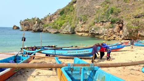 local indonesian fishermen taking traditional boat out of ocean water, slow mo
