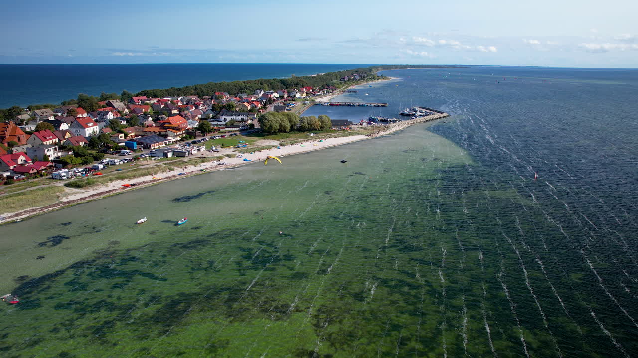 High-angle shot of a seaside town with houses, beach, and shallow green waters