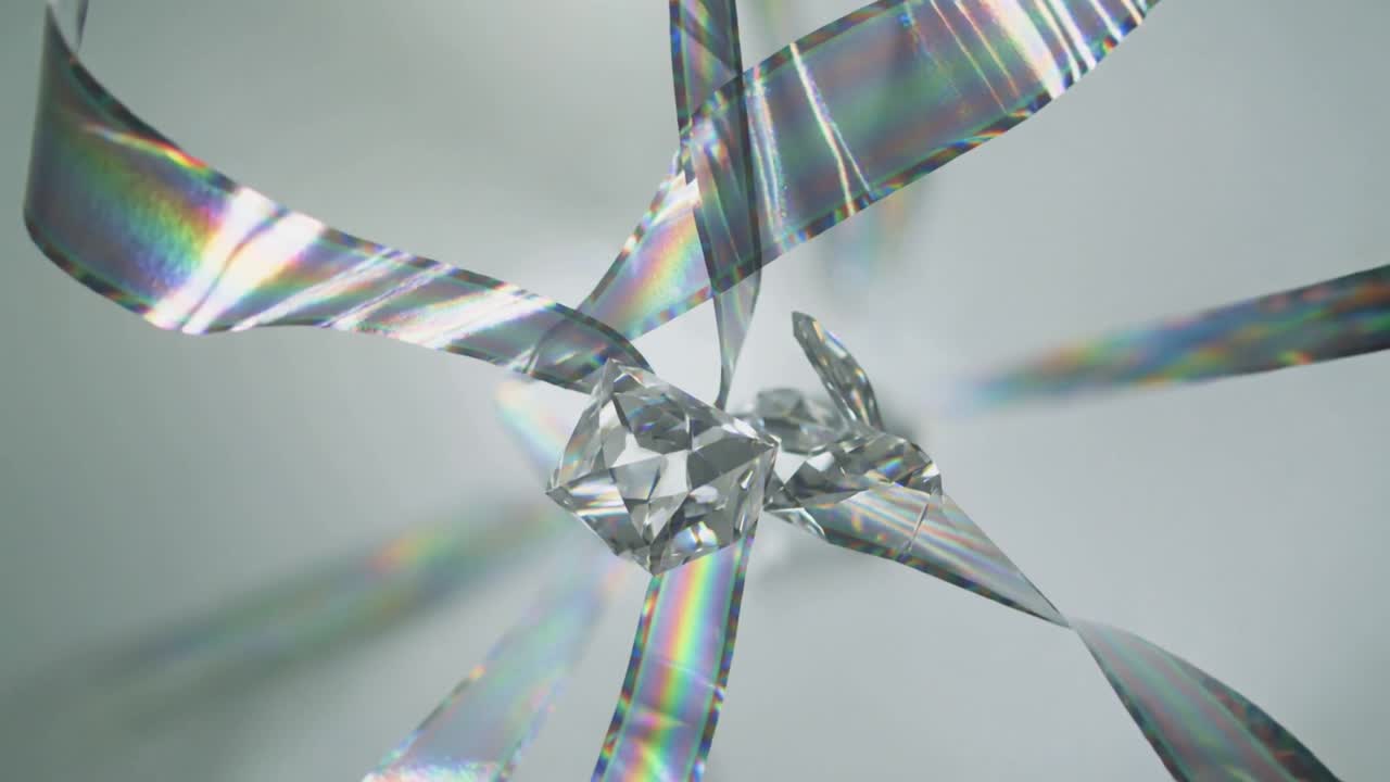 Moving cut crystal as metallic ribbons sweeping inward, scattering rainbow bands in grey studio