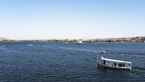 wide shot of boats sailing in the nile river in luxor egypt tranquil water and rocky banks