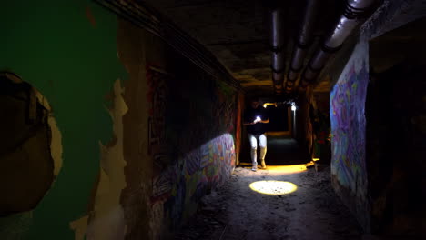 exploring a graffiti-covered underground tunnel with a flashlight