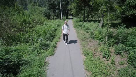 young man walking with guitar on street near forest