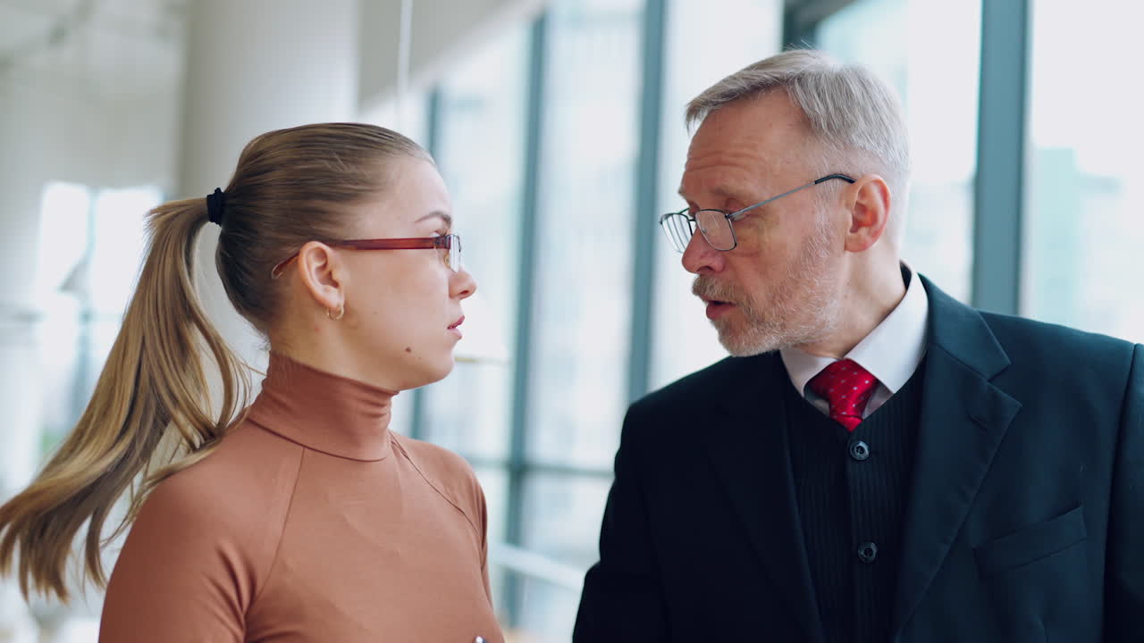 Mature businessman and secretary argue indoors. Young woman proves something to her boss and he denies. Business concept.