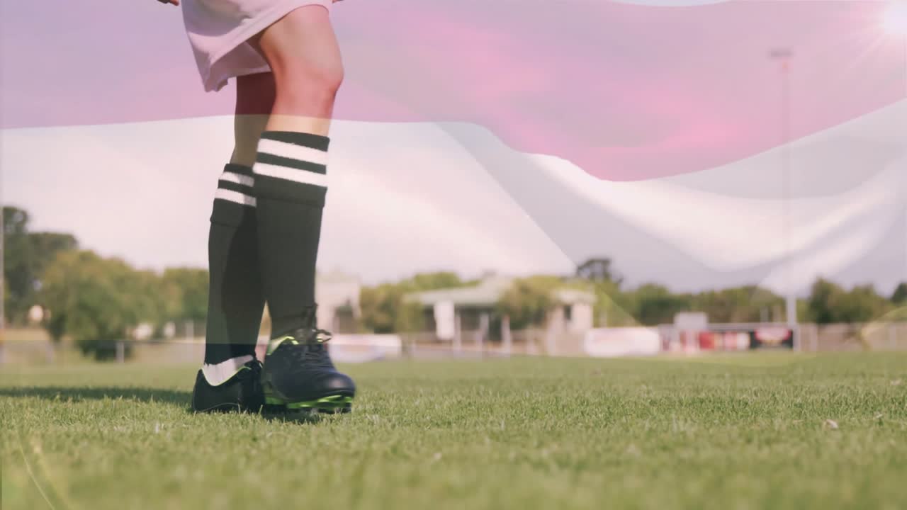Mulher de chuteiras tocando a bola de futebol, entrando para treinar drible e chute no campo.
