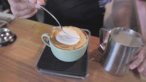 waiter makes a cappuccino decorated with milk