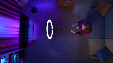 woman creating social media content in a living room at night using a ring light