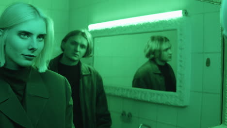 joven pareja mirando en el espejo en el baño con luz verde