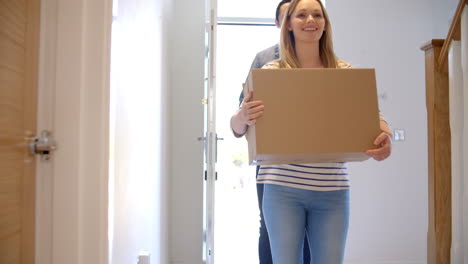 couple carrying boxes into new home on moving day