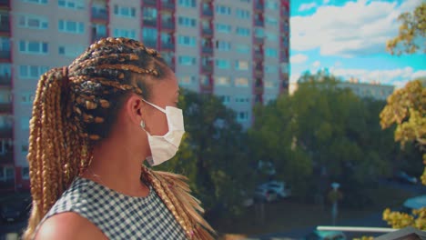 pretty young african american woman with braids and a face mask standing outside during covid-19 virus outbreak, full frame