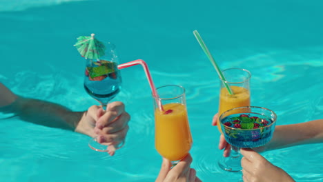 amigos brindando cócteles en una piscina