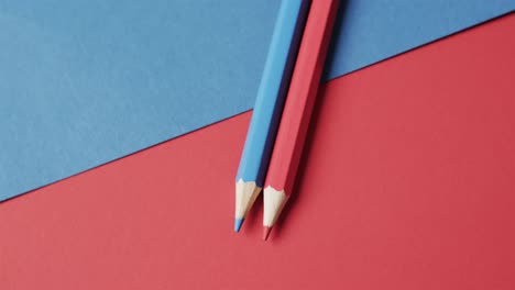 overhead view of blue and red crayons on red and blue background, in slow motion