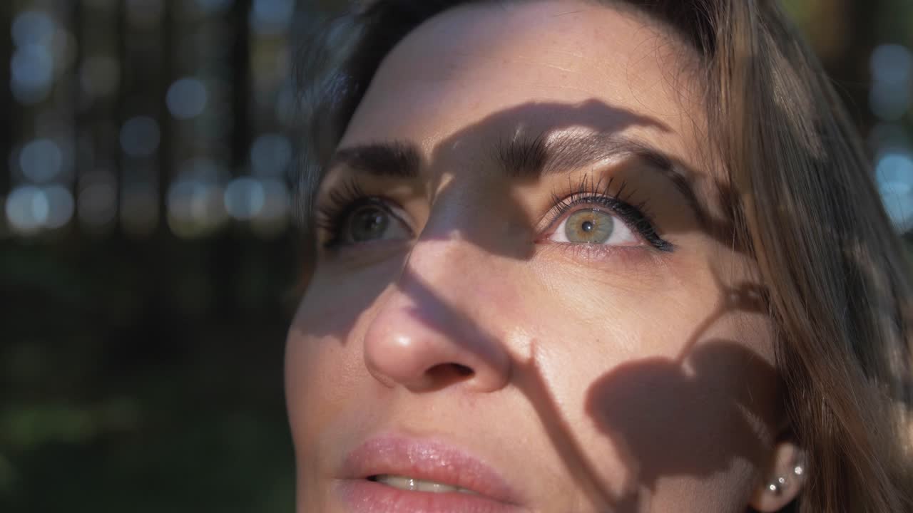 Sunlight casts tree branch shadow on woman's face