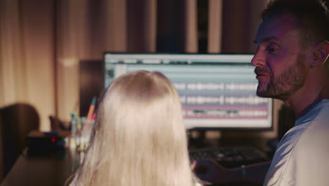 niño con instructor en estudio de grabación de primer plano. hombre muestra gráficos de grabación en la pantalla de la computadora a la niña en la sesión vocal. desarrollo musical del niño