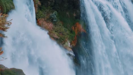 close-up view of a powerful waterfall cascading down rocky terrain with lush vegetation