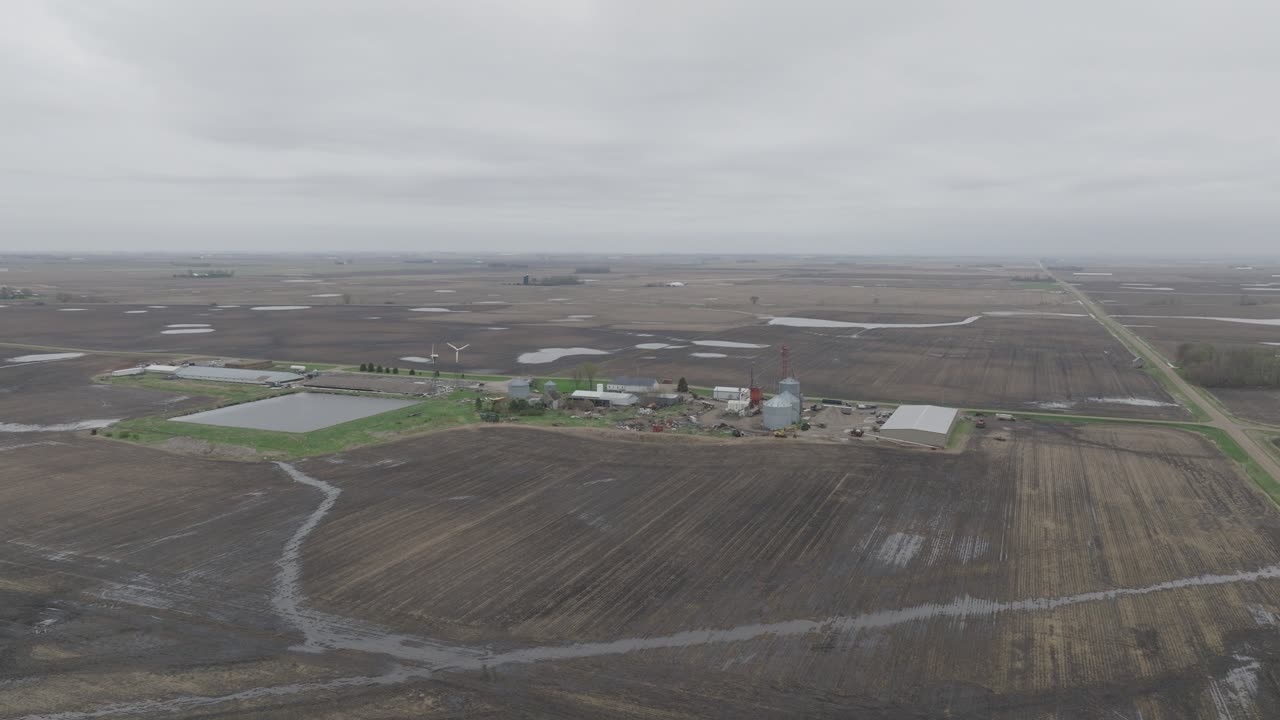 Aerial View Of Vast Fields With Silo Facility On A Gloomy Day.