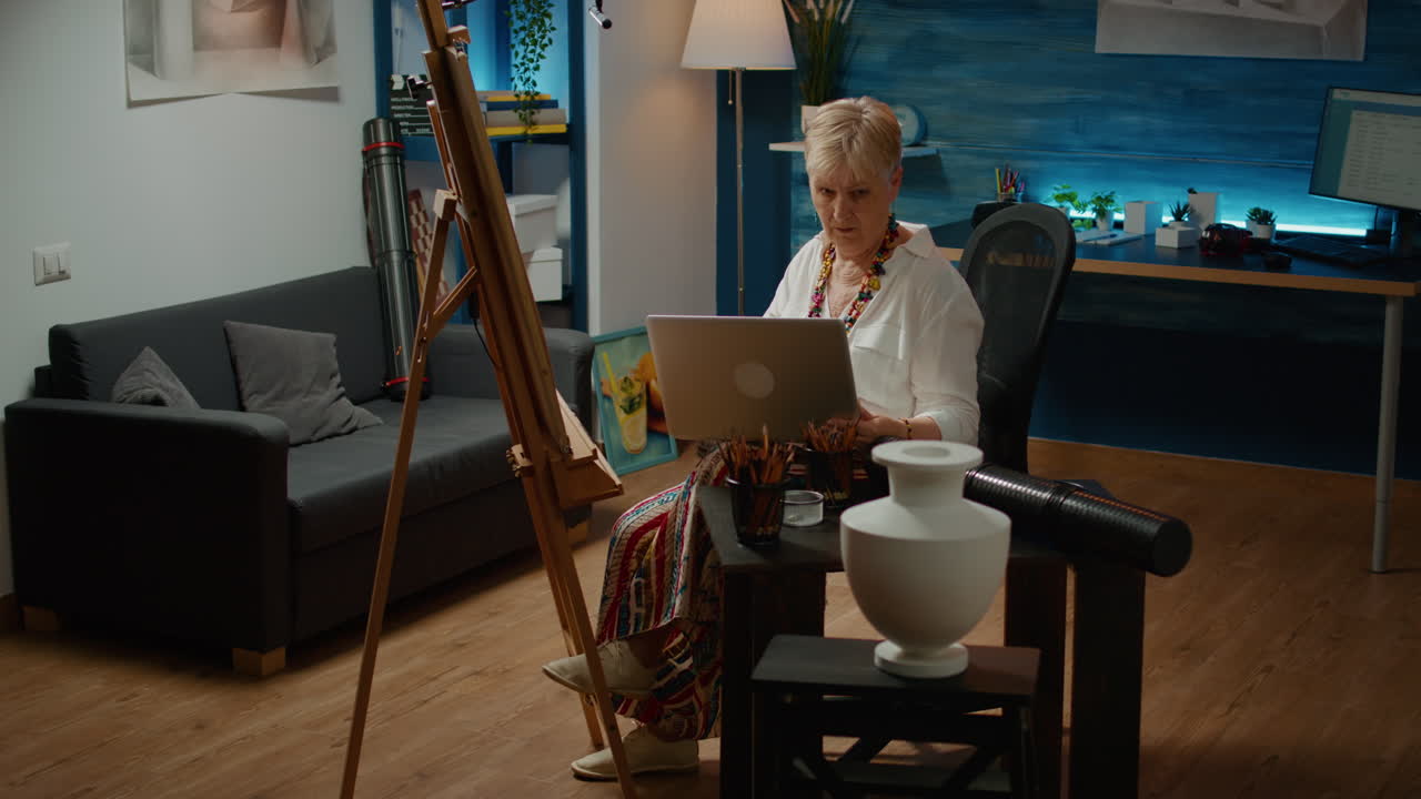 Old woman using laptop to search artistic inspiration on internet