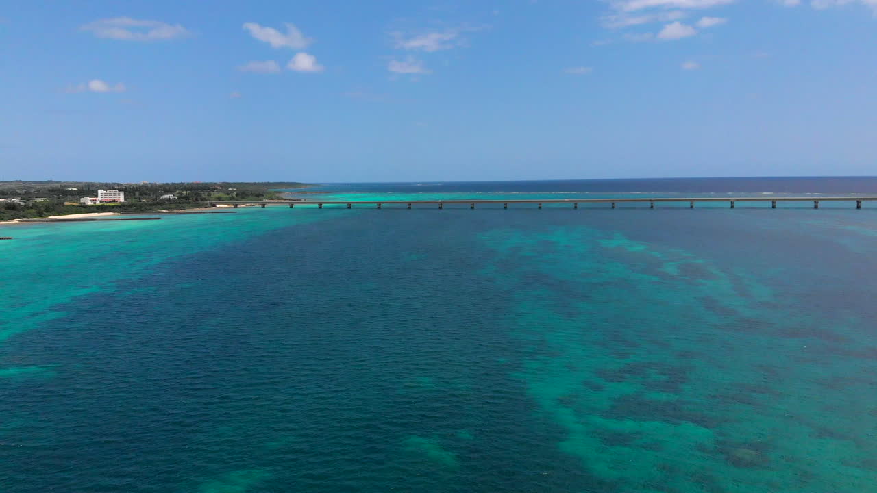 vista aérea del agua turquesa con autos pasando el puente kurima en el fondo en un día soleado de verano, miyakojima, japón