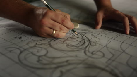 unknown man making pattern for wooden product indoors. man drawing floral decor