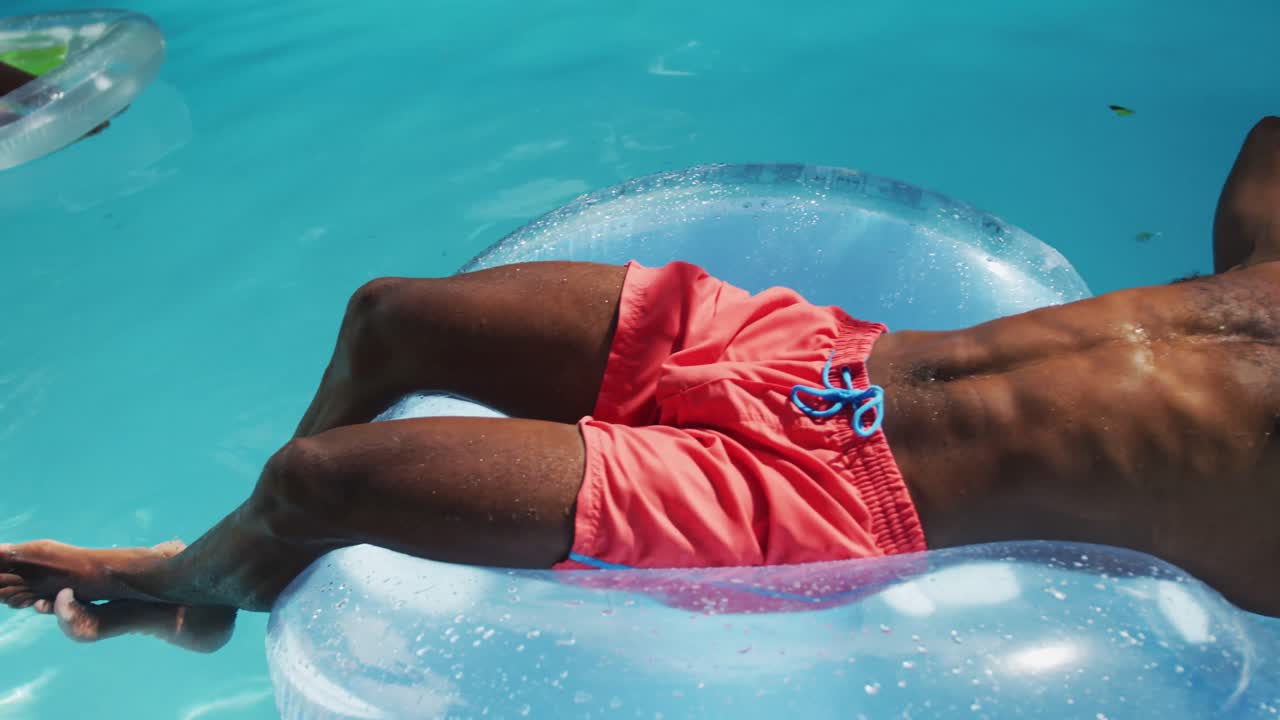 Handsome african american man lying on inflatable sunbathing in swimming pool