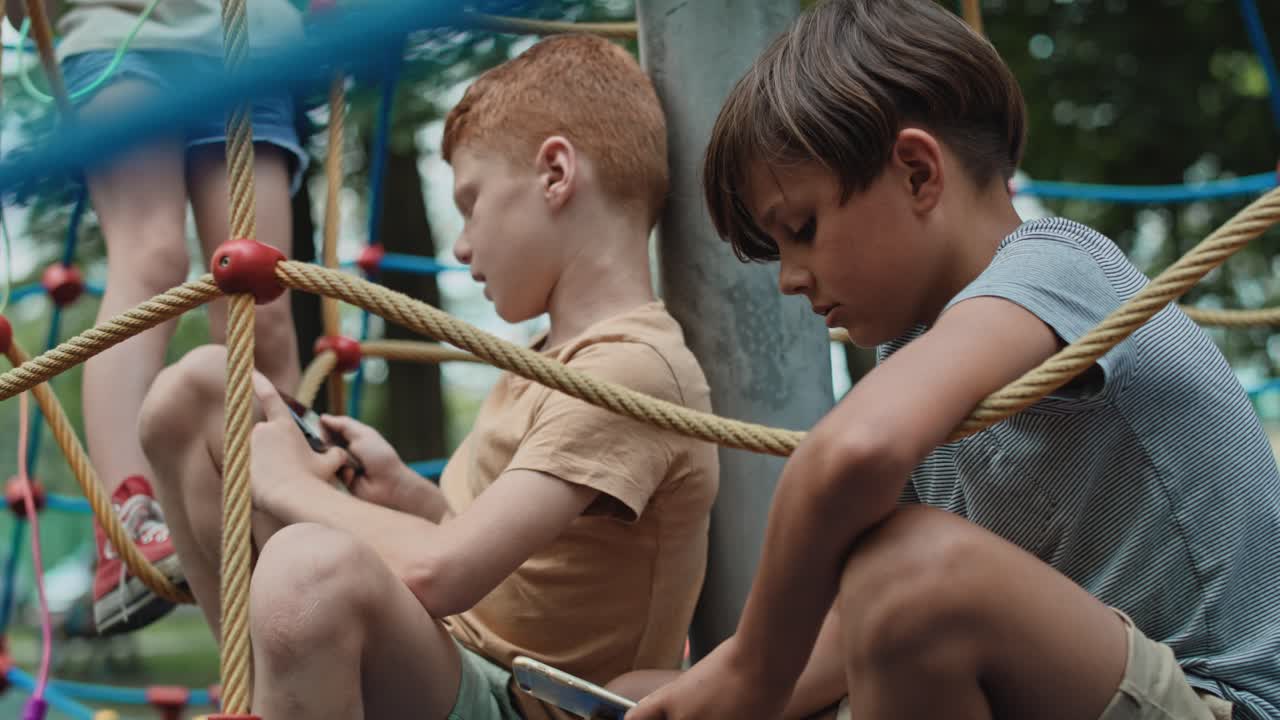 Group of boys using mobile phone at the playground.