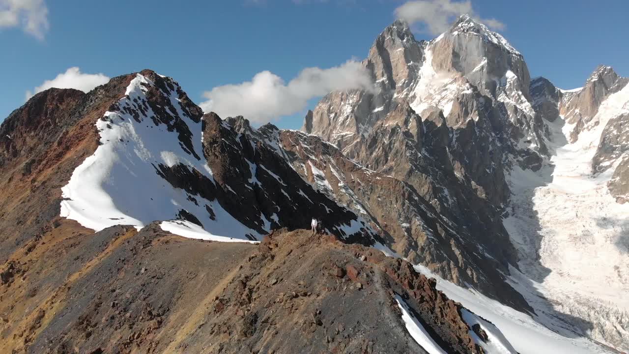 clip aéreo de dos excursionistas cerca de la cima de un monte nevado ushba, georgia, durante un día soleado
