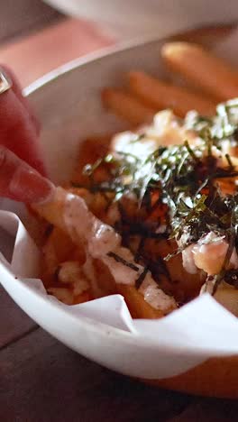 hand reaching for seasoned fries in bowl