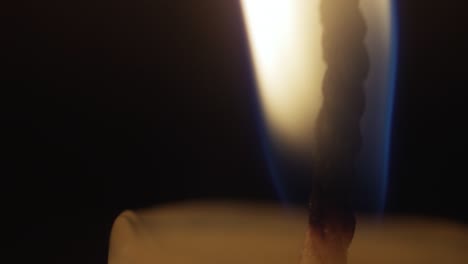 close-up of a candle flame on a black background. macro shot of candle wick. slow motion