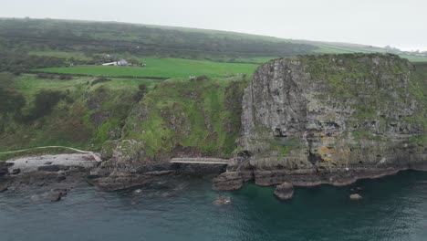 Aerial-dolly-backwards-shot-of-majestic-cliffs-by-the-sea-from-the-Gobbins-Cliffs-while-traveling-through-the-gorgeous-Northern-Ireland-on-a-calm-morning