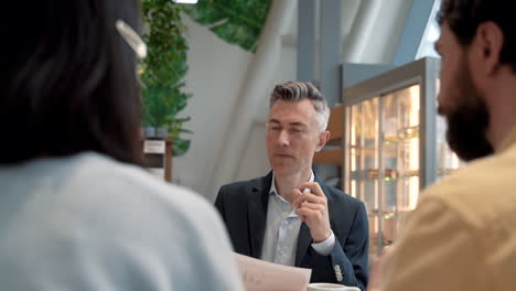 un hombre de negocios atractivo entrevista a dos personas para un trabajo en una cafetería 1