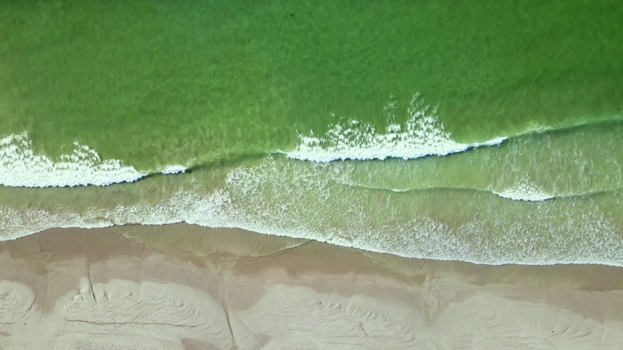 las suaves olas del océano acuamarino se rompen en la playa de arena, desde arriba hacia abajo
