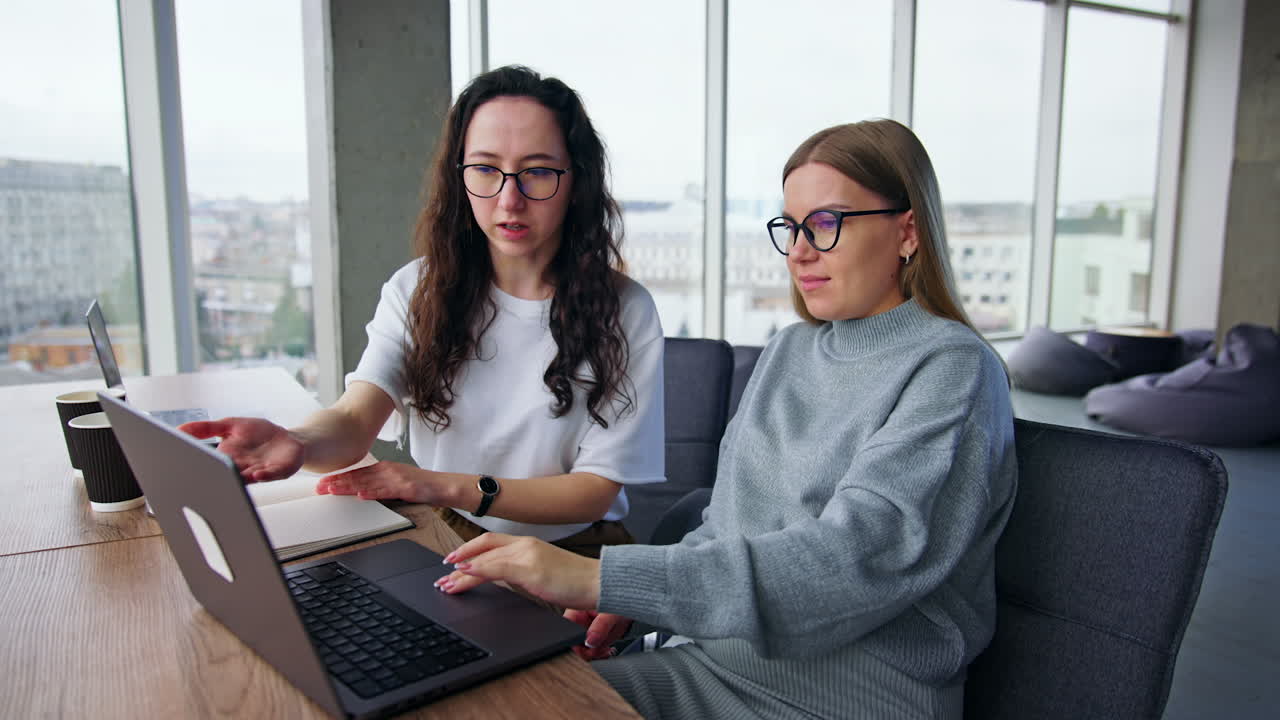 Active positive female workmates look at laptop discussing the issues. Women watching video files or images.