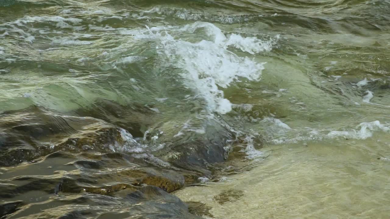 Flusso d'acqua turbolento su rocce e sabbia, spiaggia tropicale, slow motion