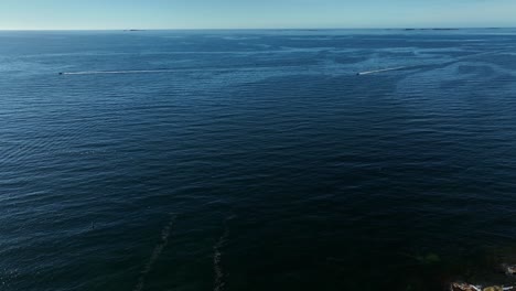 Vida-Silvestre-En-Acción-Con-Aves-Volando-Sobre-El-Océano-Atlántico-Frente-A-La-Costa-Del-Brazo-De-Joe-Batt-En-La-Isla-De-Fogo,-Canadá,-Con-Un-Dron-Aéreo-Sigue-La-Orilla-Panorámica-Inclinándose-Hacia-Abajo-Con-El-Horizonte-A-La-Vista