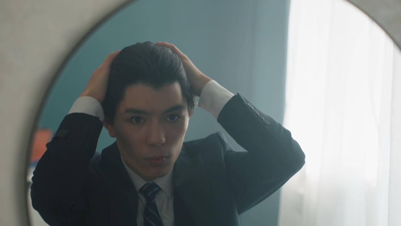 Asian man in suit adjusting hair in round mirror under soft window light, cufflink and tie visible, quiet bedroom scene, anxious yet determined expression, lastminute grooming ritual before big