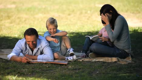 children doing homework with parents on the grass