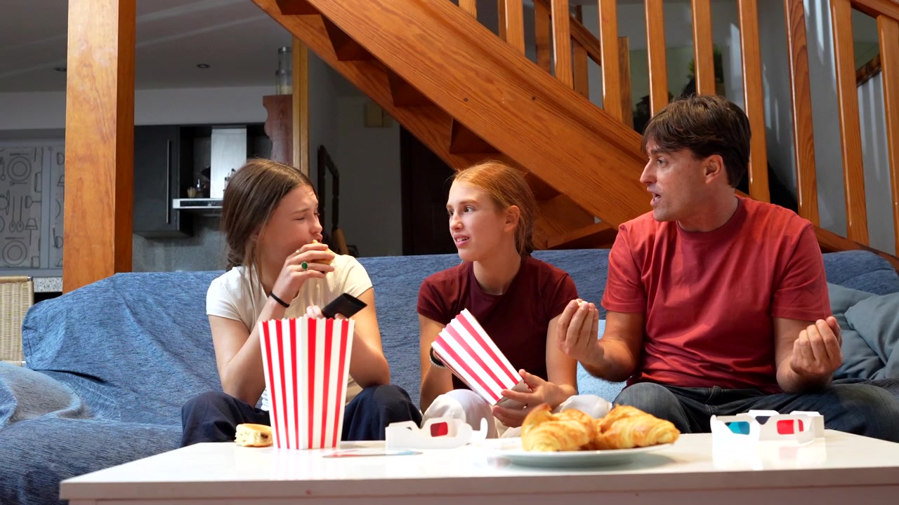 Familie schaut Film und isst Popcorn auf dem Sofa