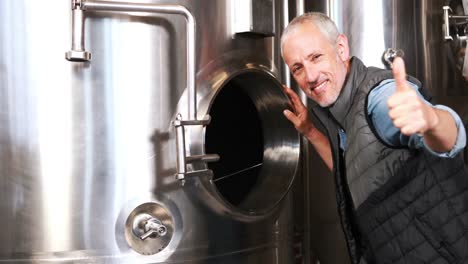 brewery worker looking into steel container with thumbs up