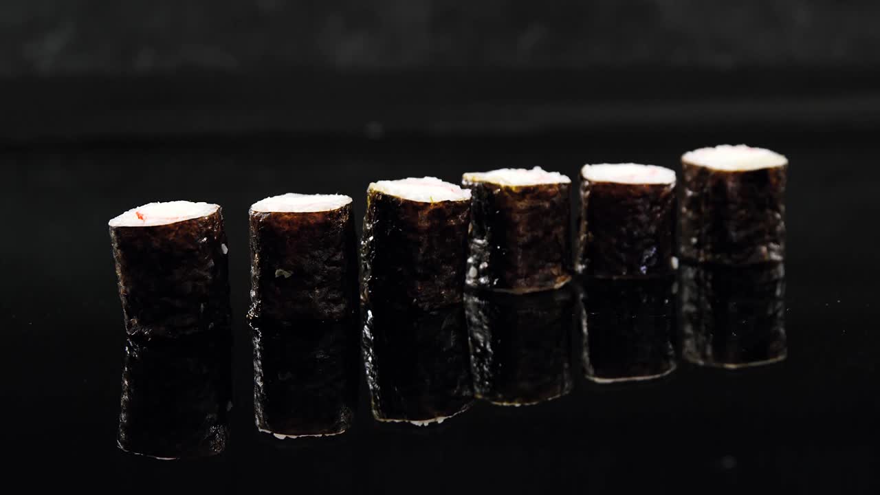 un rollo de sushi de maki servido sobre un fondo negro