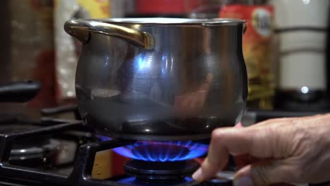 turning on stove flame and stirring soup on pot