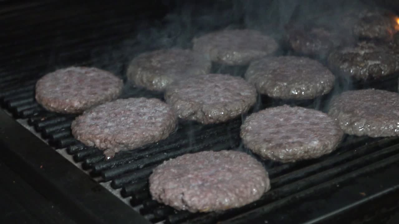 Lækker oksekødsburger, der tilberedes på en varm grill.