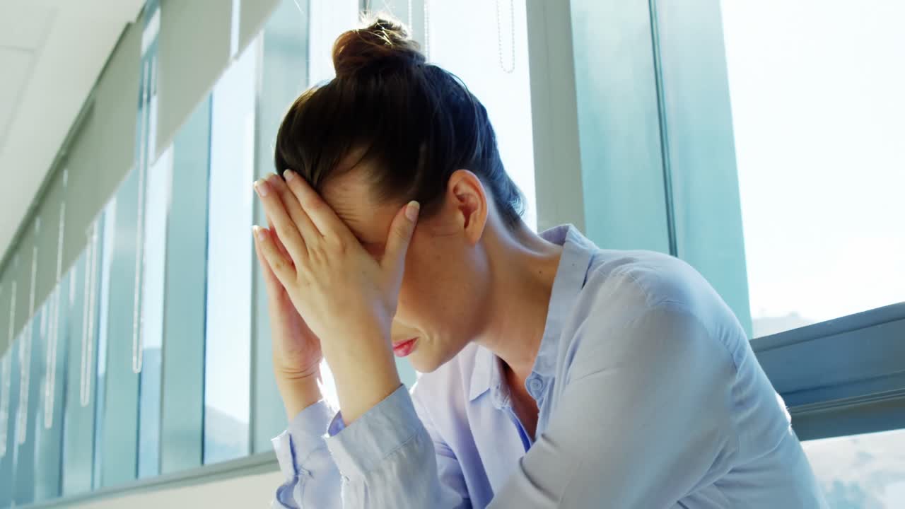 이마에 손을  ⁇ 고 앉아 있는 긴장 된 여성 비즈니스 임원