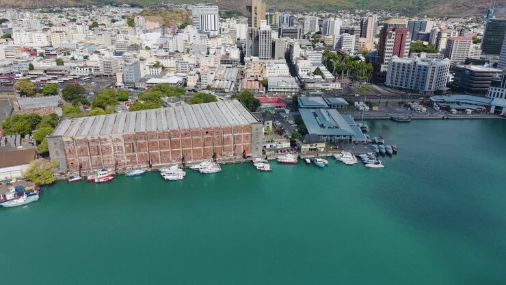 Vista aérea do porto de Port Louis, em Maurício, com o histórico Customs Warehouse, a área de Caudan Waterfront e vários barcos atracados na água turquesa