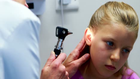 female doctor examining patient ear with otoscope