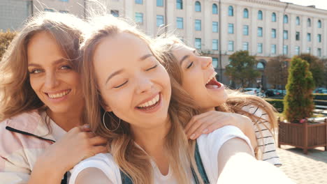 three friends kissing and laughing in city selfie