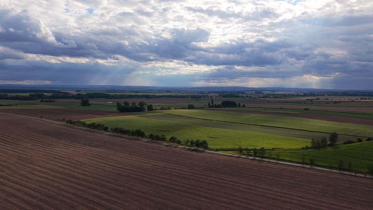 Sunlight shines through the clouds on the Czech fields. Farming in Europe in hot summer. Drone view